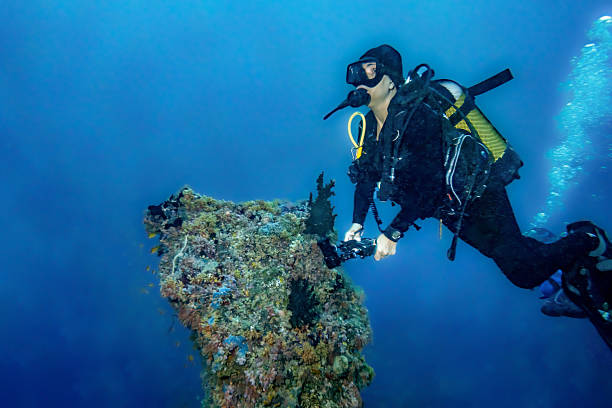 Underwater photo two clownfish  -  Anemone fish couple   and man scuba diver, filming  with action underwater camera. coral  Sea life  Coral garden reef.\nMiddle East,  Red Sea,  Egypt
