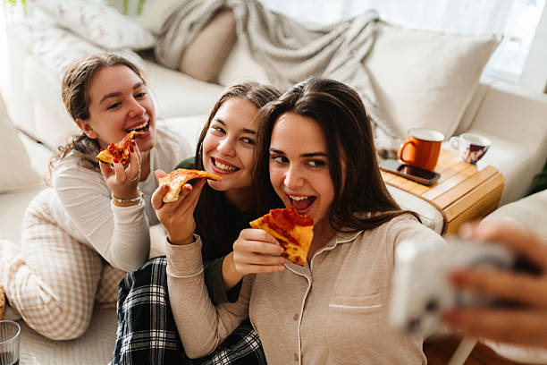 istock Friends smiling and taking selfie while eating pizza indoors 2252566241
