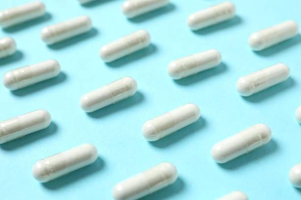 istock White medical capsules on blue background 2252567883