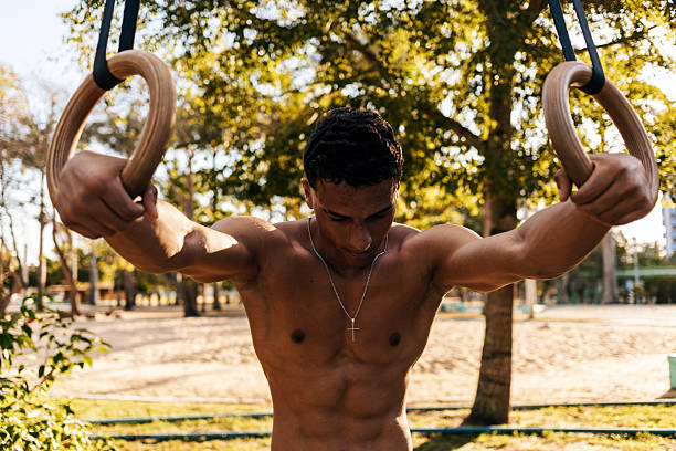 Athlete resting on gymnastic rings during outdoor calisthenics training
