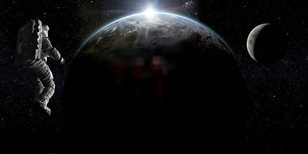 A single astronaut in full spacesuit in zero gravity in space looking at the sun rising from behind planet Earth with the moon in the distance.