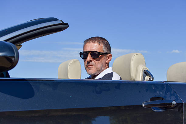 Handsome Caucasian Male Security Agent Safeguarding Luxury Vehicles for VIPs with Walkie Talkie in Corporate Business Setting.