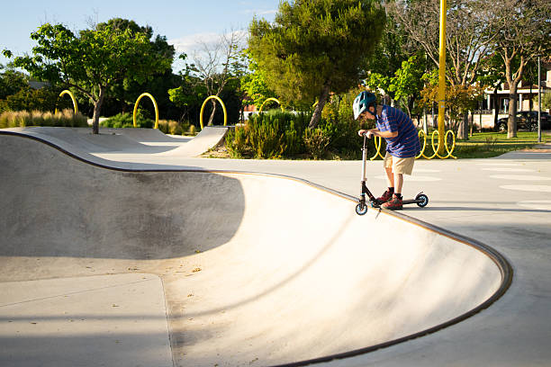 Boy carefully riding his push scooter in a skate park