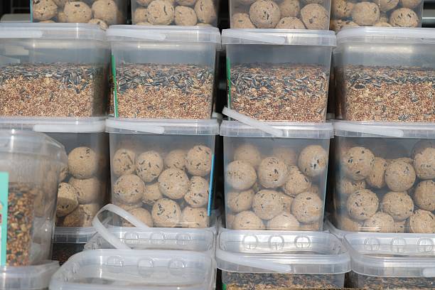 A collection of transparent containers filled with bird seed and feed balls, showcasing various textures and colors for bird enthusiasts. in Kempten