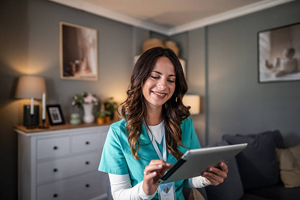 istock Smiling nurse using digital tablet for home healthcare visit 2252576207
