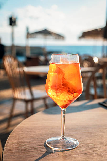 istock Spritz cocktail with ice in a wine glass on a seaside cafe table. Refreshing summer aperitif with blurred beach background 2252581311