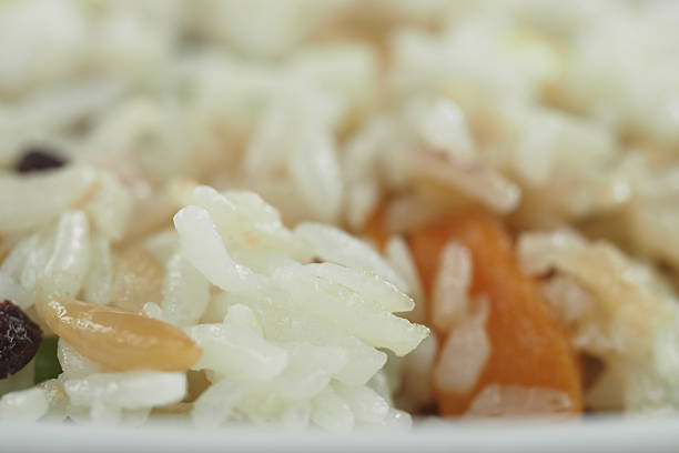Close-up of a tasty rice dish with veggies and nuts on a plate.