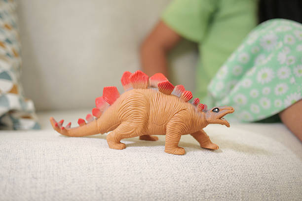 istock Child plays with a colorful dinosaur toy on a couch 2252585160