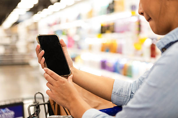 istock Using smartphone in a shopping aisle, looking at product details on screen 2252586494
