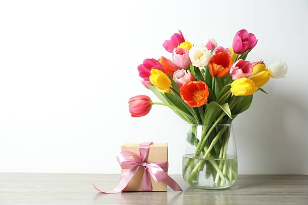 Beautiful fresh tulips in a vase with gift box on the table