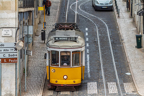 High angle view of the yellow Tram 28 driving on curved cobblestone tracks in the historic center of Lisbon, Portugal. Lisbon Portugal, 23 March 2015.