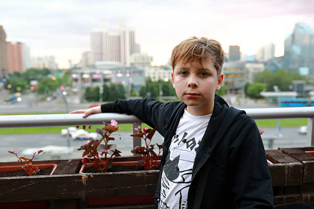 istock Boy standing on balcony with city skyline in background 2252589235