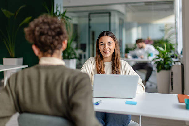 istock Discussion between two colleagues in a modern office while working on a project together with laptops and plants around 2252589368