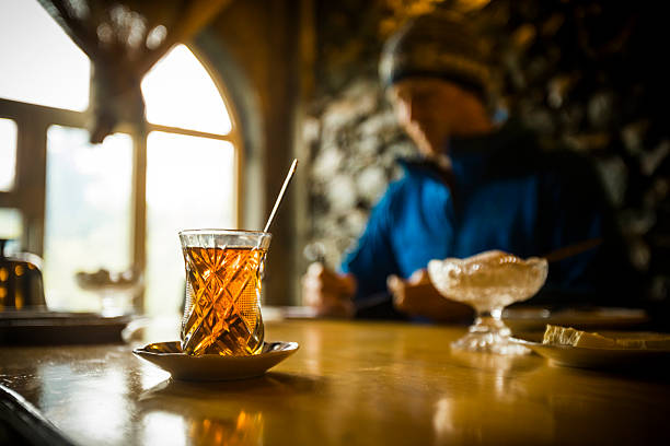 Selective focus from hot tea and snack on counter to man in restaurant, Lahic, Greater Caucasus