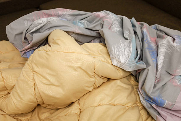 istock A soft yellow duvet and grey bed linen with a delicate feather pattern lie in a messy pile, creating an atmosphere of home comfort and morning relaxation. 2252590694