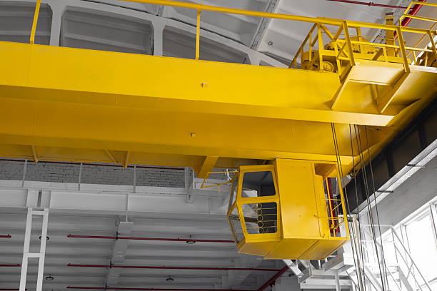 istock Industrial workshop with an overhead crane fire safety system red pipes. A bright yellow crane is suspended from the ceiling. Concept of industry, manufacturing, engineering, interior 2252591849