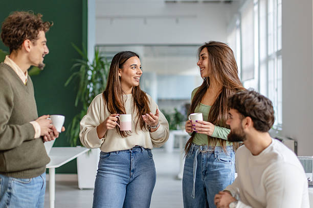 istock Group of colleagues engaging in conversation while holding coffee cups at a modern office space during work hours 2252592168