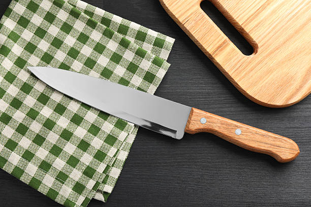 istock One sharp knife, napkin and board on black wooden table, flat lay 2252592548