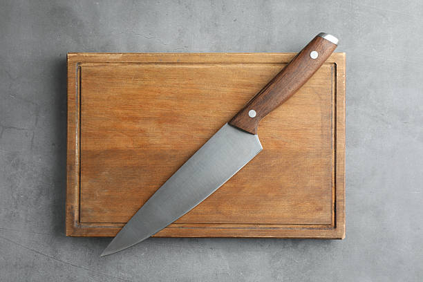 istock Knife and wooden board on grey textured table, top view 2252592565