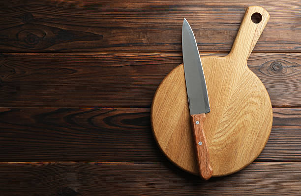 istock Knife and board on wooden table, top view. Space for text 2252592586