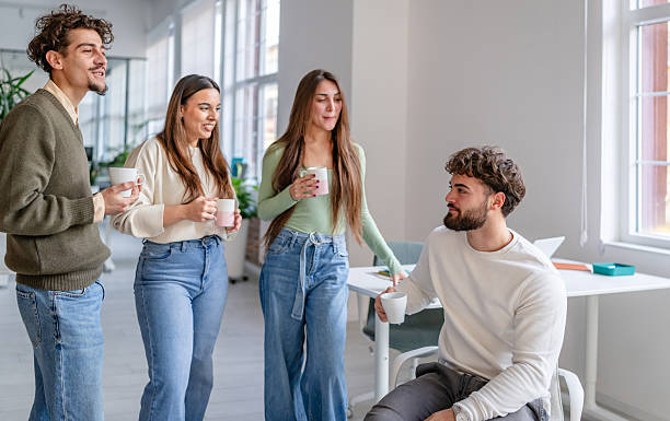 istock Group of young adults talking and enjoying beverages in a modern office space during working hours 2252593945