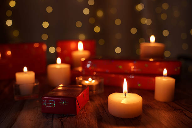 istock cozy holiday setting with glowing candles surrounding stacked red gift boxes against a warm bokeh background on a wooden surface, giftgiving, relax, wrapped, 2252602657