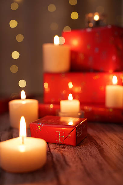istock warm festive scene with glowing candles and stacked red gift boxes on wooden surface, enhanced by soft golden bokeh lights, creating a cozy and inviting holiday atmosphere, blur, calm, gentle 2252602683