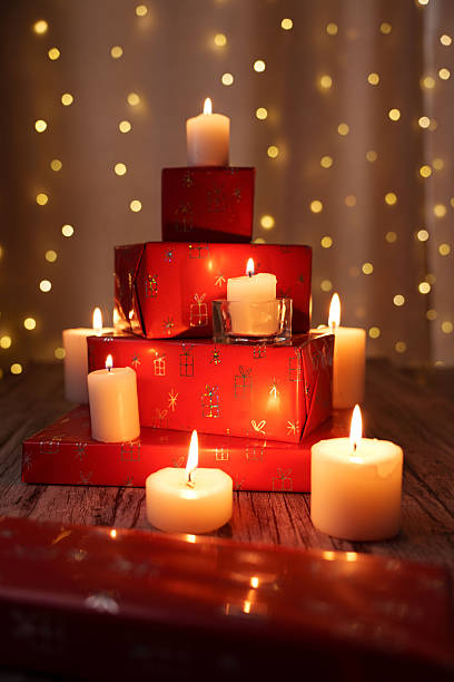 istock cozy holiday setting with glowing candles surrounding stacked red gift boxes against a warm bokeh background on a wooden surface, giftgiving, relax, wrapped, ornamental, lightbulbs, gold, calmness 2252603227