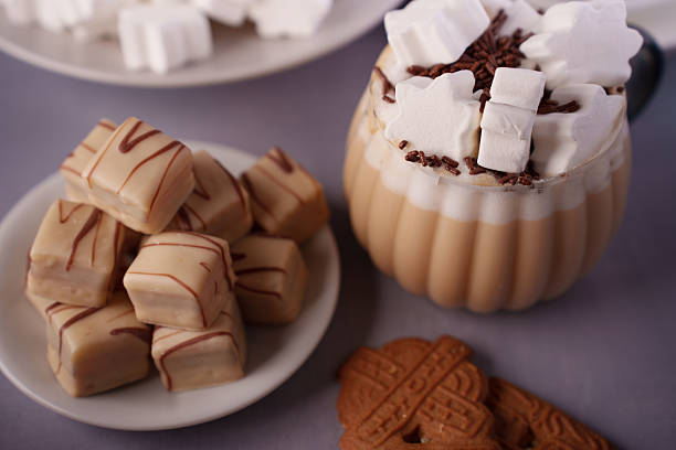 istock cozy indulgence: frothy beverage topped with marshmallows and chocolate sprinkles, paired with delicious caramel fudge and spiced biscuits on a textured surface, delight, treat, luxury, special 2252603323