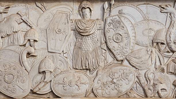 Rome, Italy - 12 January 2025. Relief at Piazza del Popolo displays detailed Roman weapons, shields, and armor arranged in a dense formation around a central suit.
