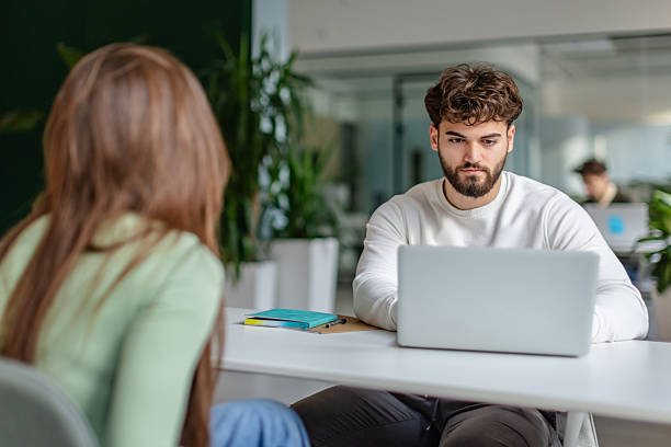 istock Two young adults work together in a modern office setting during the day, focused on tasks at their laptops 2252604524