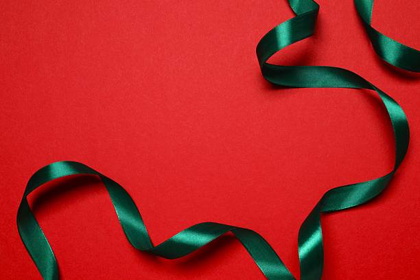 istock Beautiful green silk ribbon on red background, space for text 2252606176