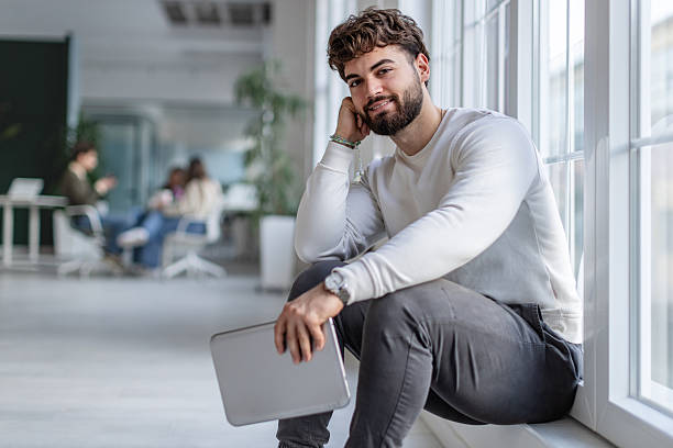 istock Young adult in office taking a break while colleagues collaborate in a modern workspace with technology 2252608481