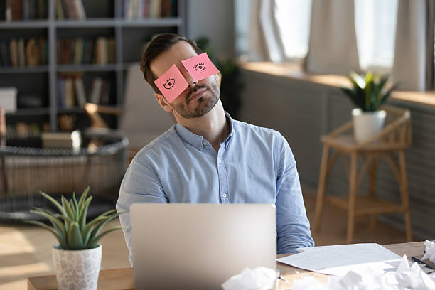 istock Businessman sleeping at workplace with sticky notes wide open eyes 2252609386