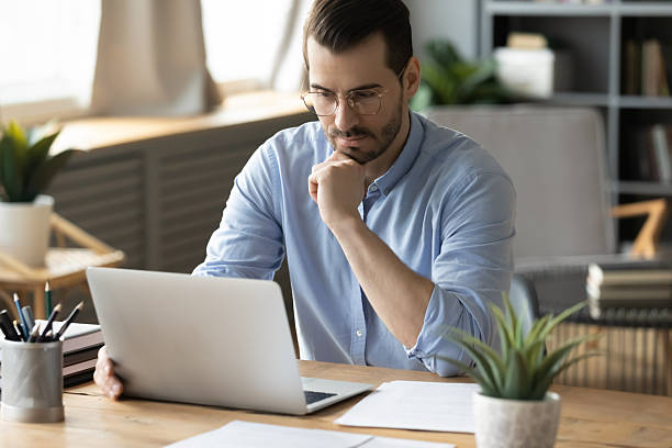 istock Pensive mid adult man office worker looking at notebook screen 2252609563