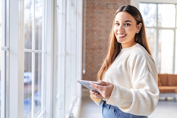 istock Young adult with tablet in modern office during work hours in bright space with large windows 2252610094