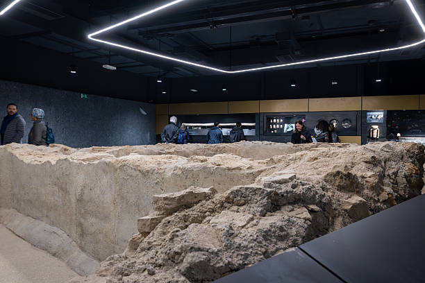 Rome, Italy - December 17, 2025: A wide view of a large ancient Roman excavation area inside the station, featuring circular stone foundations and defensive masonry walls.