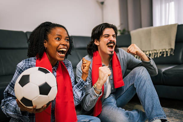 istock Multiracial Couple Cheering Soccer at Home 2252616021