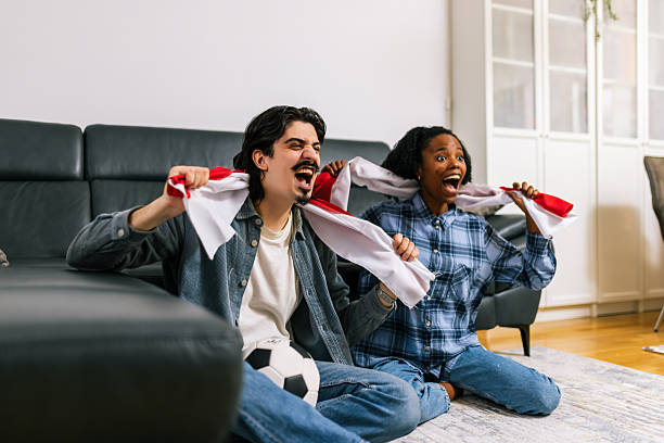 istock Multiracial Couple Cheering Soccer at Home 2252616114