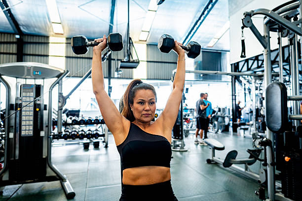 istock Mature woman doing shoulder press with dumbbells at gym 2252616421