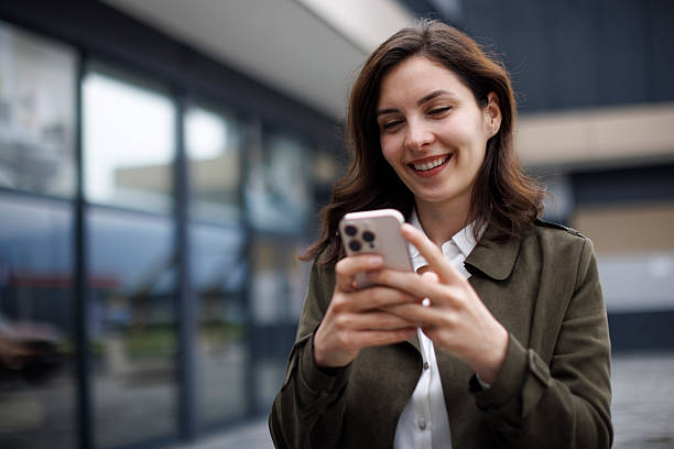 istock Smiling Young Woman Messaging on Mobile Device Outdoors 2252617070
