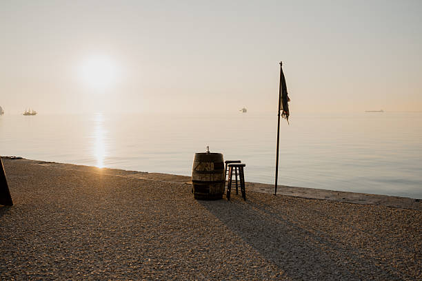A quiet waterfront scene at sunrise in Thessaloniki, Greece. Calm sea, soft morning light and minimal urban elements create a peaceful atmosphere along the coastal promenade.