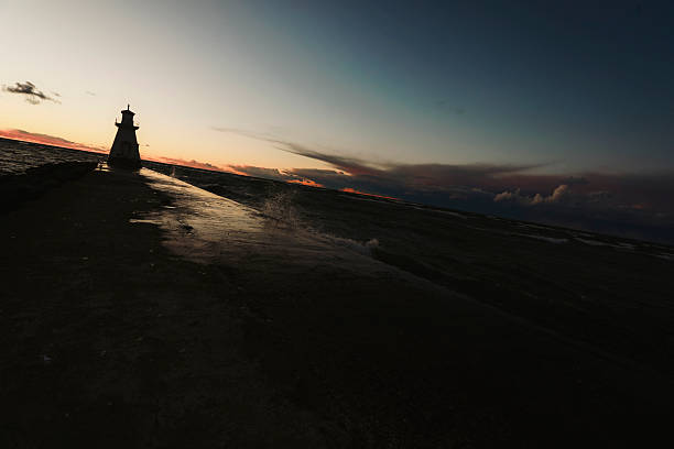 A lighthouse in the setting sun along the shores of Lake Huron. Windy day with rough waters. Shot with a Canon 5D Mark IV.