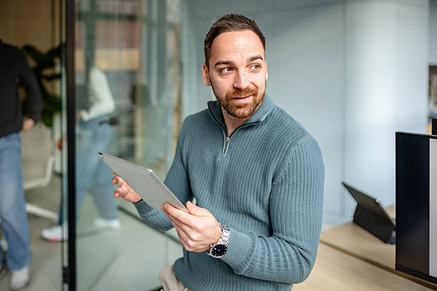 istock Man holding tablet in office while engaging with coworkers during a work session 2252622964