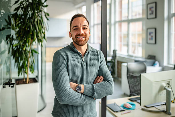 istock Professional man smiling in modern office environment during work hours engaging with colleagues and technology 2252625547