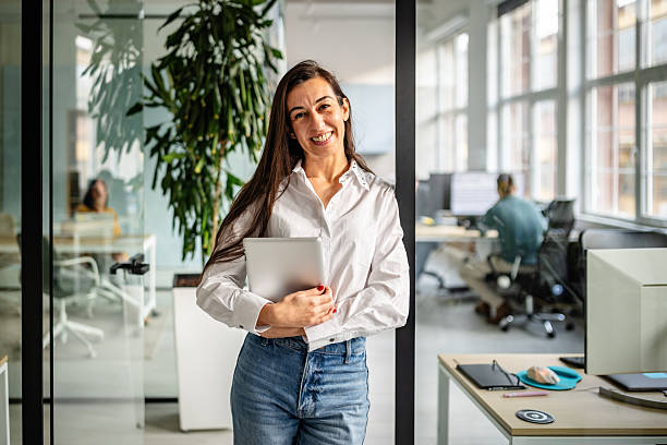 istock Professional woman engaged in work activities in a modern office setting with colleagues in the background during daylight 2252625692
