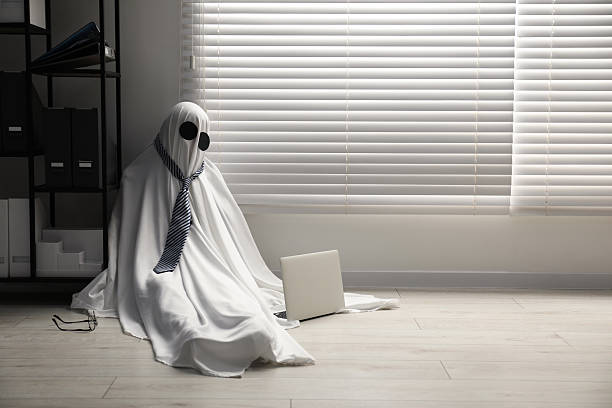 istock Overworked ghost. Man in white sheet with laptop on floor in office, space for text 2252629172