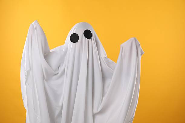 istock Creepy ghost. Person covered with white sheet on yellow background 2252629294