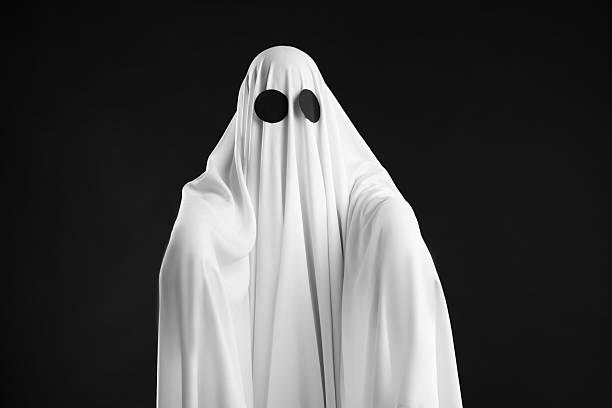 Creepy ghost. Person covered with white sheet on black background