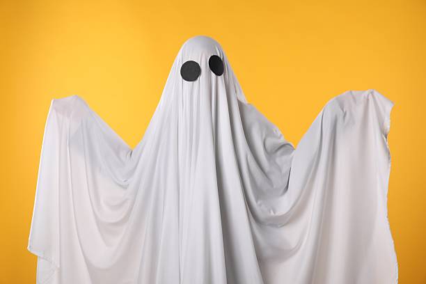 istock Creepy ghost. Person covered with white sheet on yellow background 2252629408